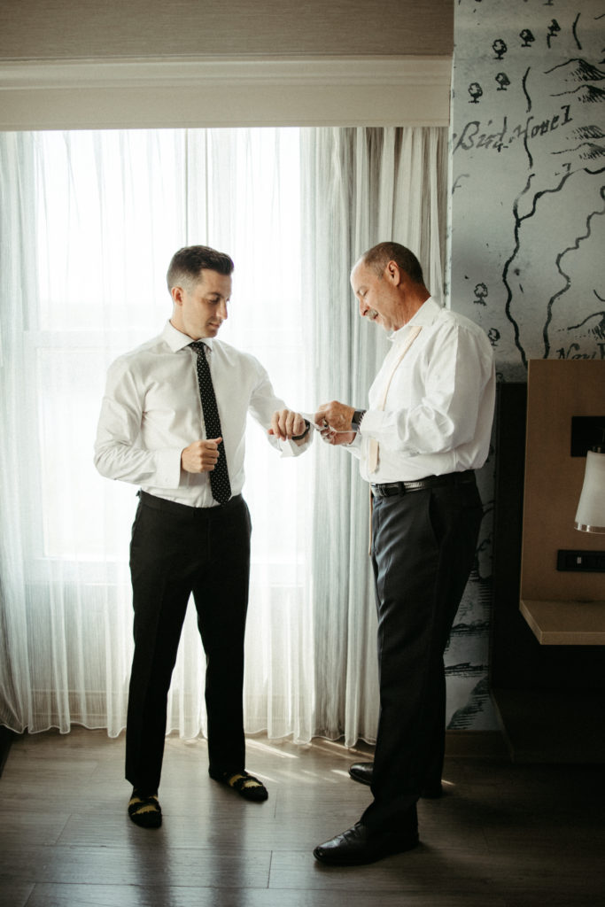 A groom getting ready for his wedding day with help from his dad.