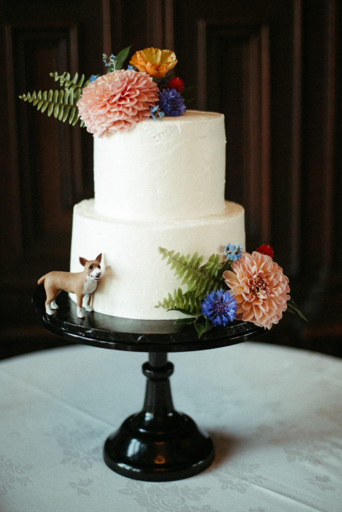 Wedding cake with florals and a dog figurine. 