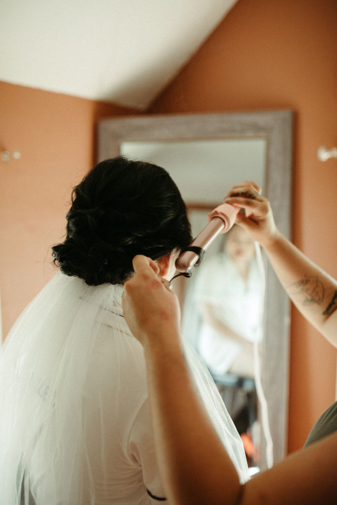 A woman in a veil gets her hair curled.