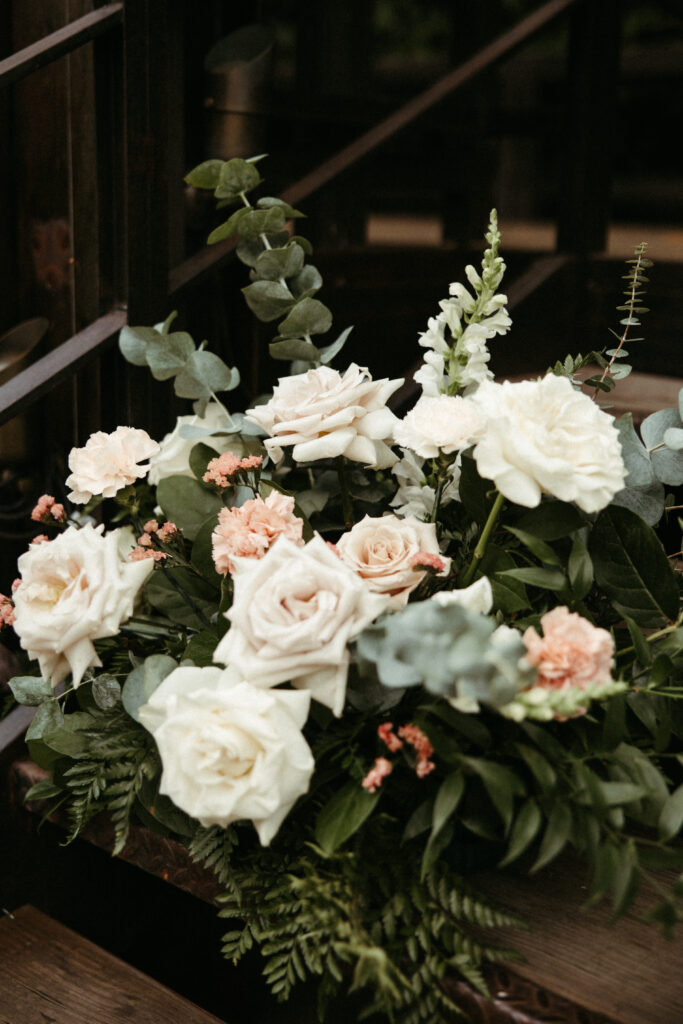 A couple exchanges vows in The Foundry's sunlit courtyard, surrounded by lush greenery and florals by Bad Boss Bride.