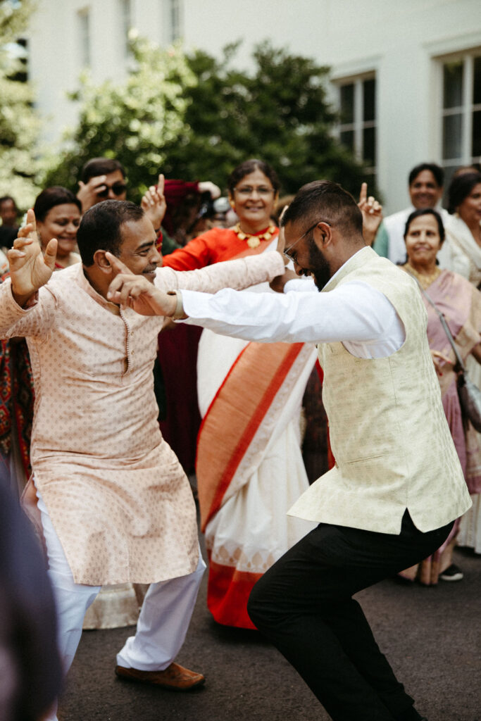 Group of guests dancing energetically to the beat of traditional dhol drums during the Baraat procession.