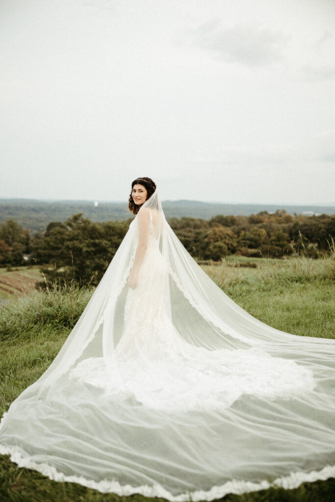 Bride's Cathedral-Length Veil: Timeless elegance captured as the bride wears a cathedral-length veil against the scenic backdrop of the vineyard.