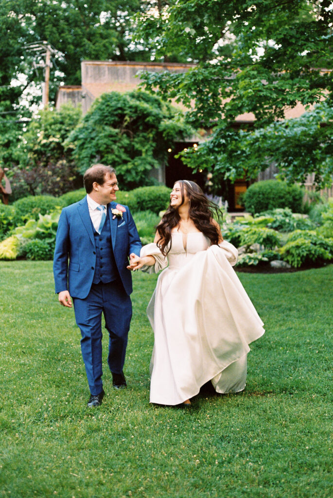 Golden hour portrait of the couple holding hands, with soft sunlight in the background shot on 35 mm film.
