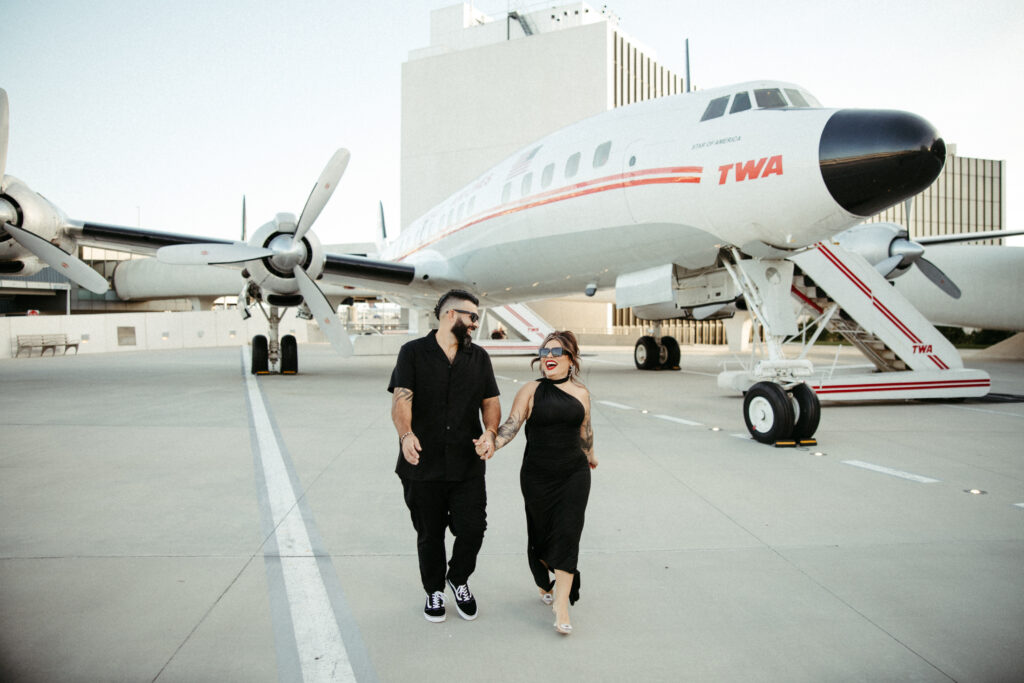 Romantic travel-inspired engagement portraits in front of the historic TWA plane.