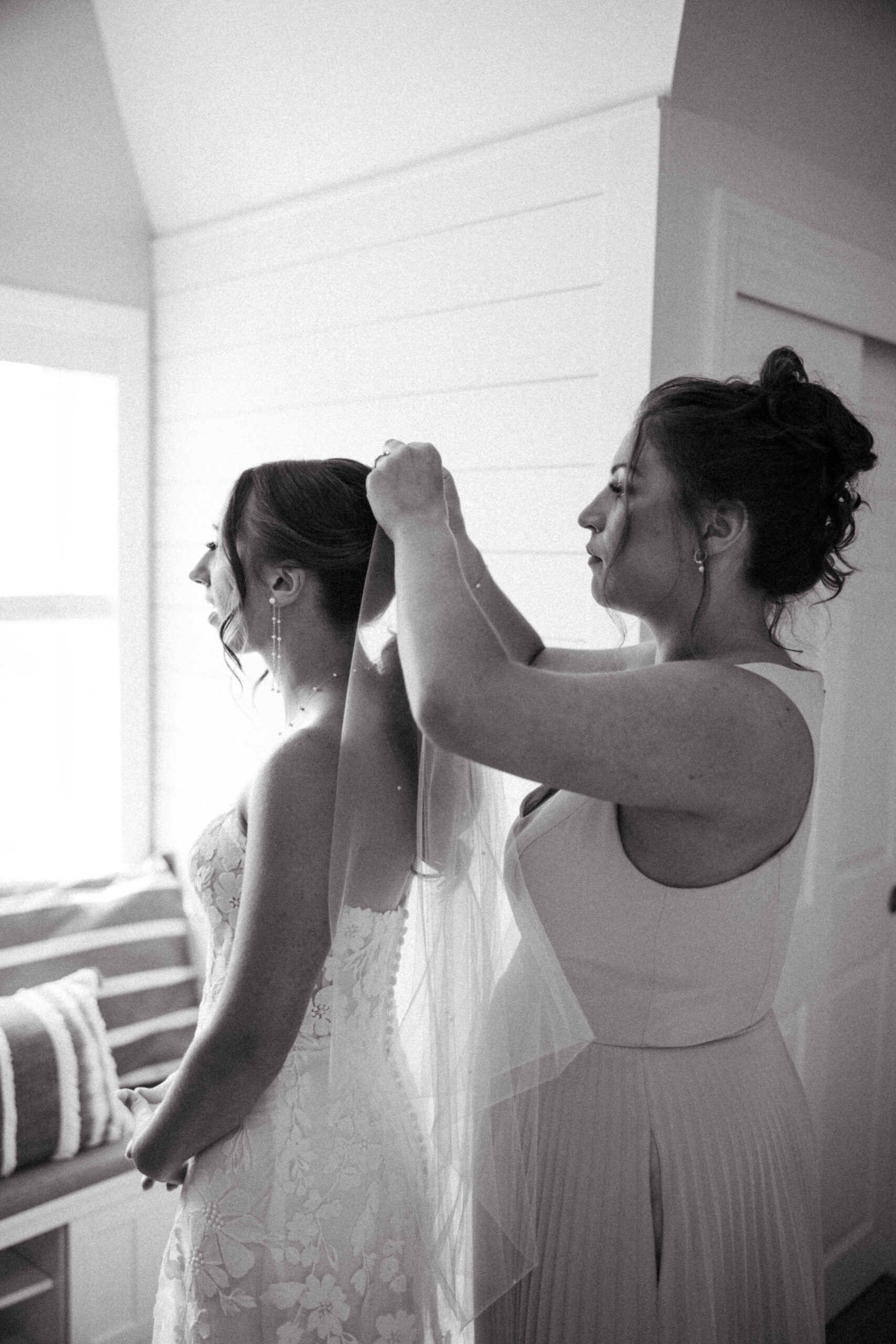 A maid of honor places a veil in the bride's hair.