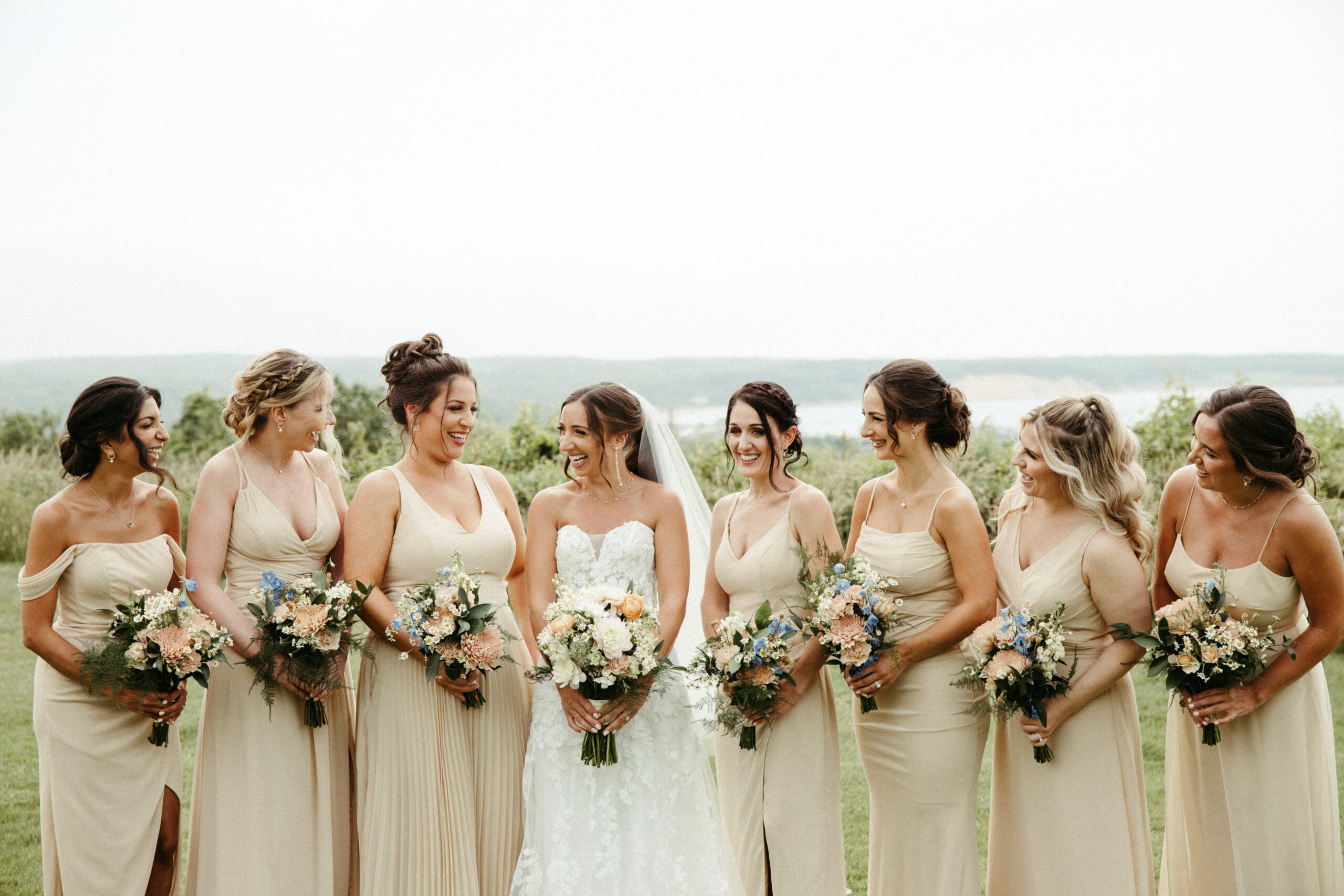 The bridal party bursts into laughter, celebrating the day with unposed joy.