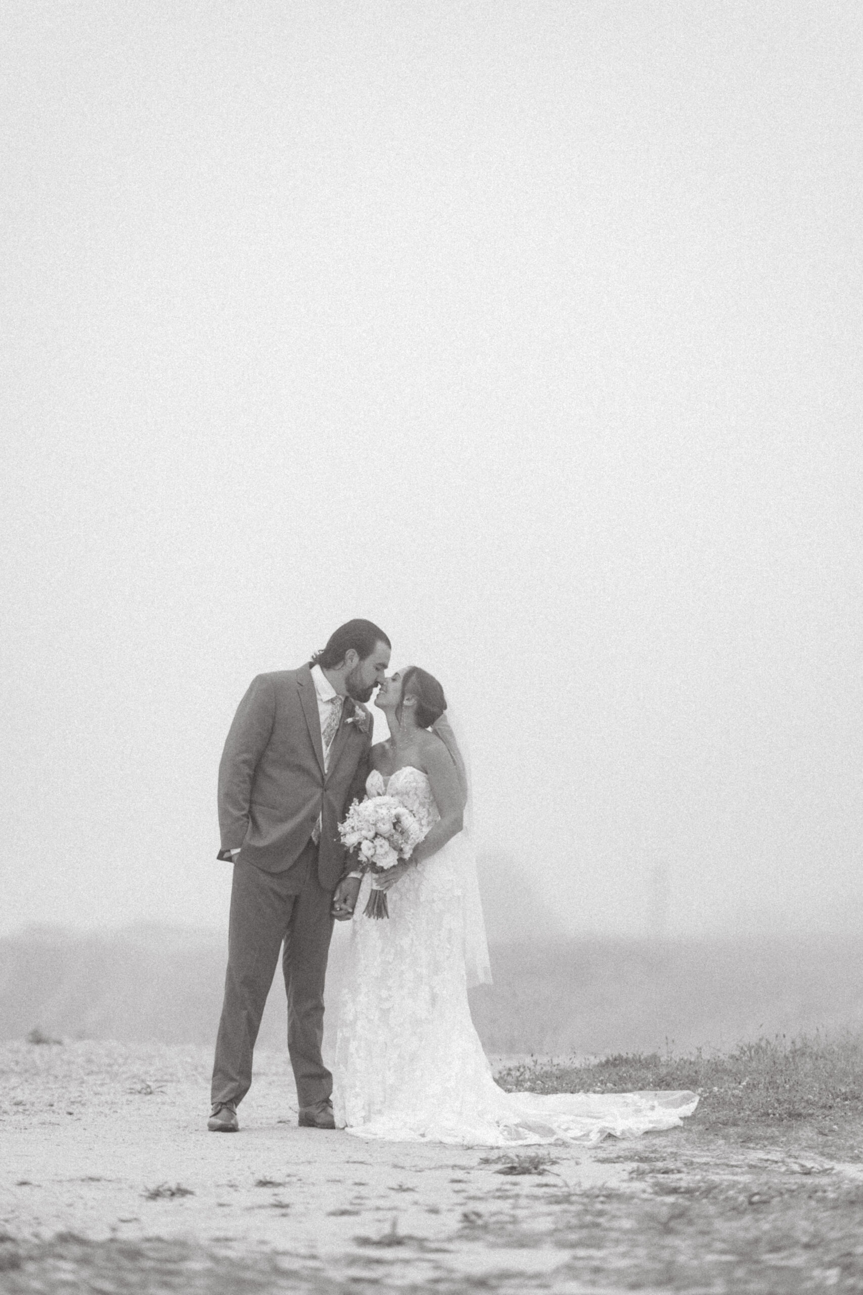 A candid, black and white image of the couple leaning in for a kiss lost in the moment.