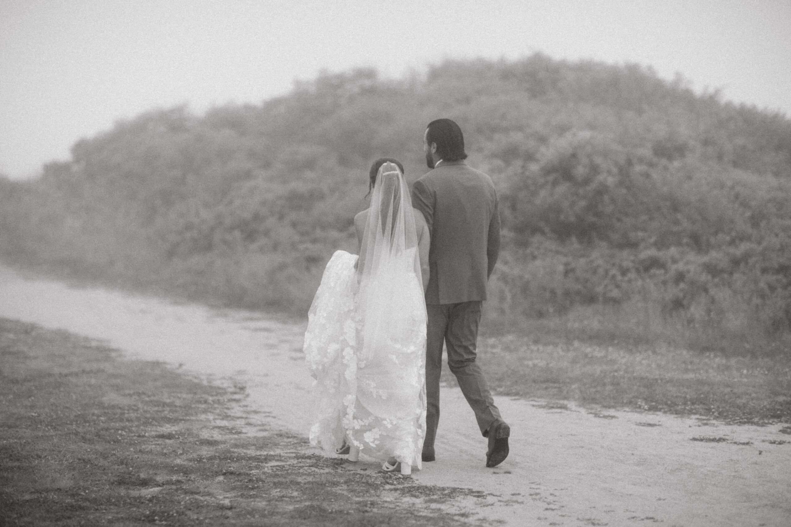 The newlyweds walk hand-in-hand along the rugged Montauk cliffs, mist surrounding them like a scene from a dream.