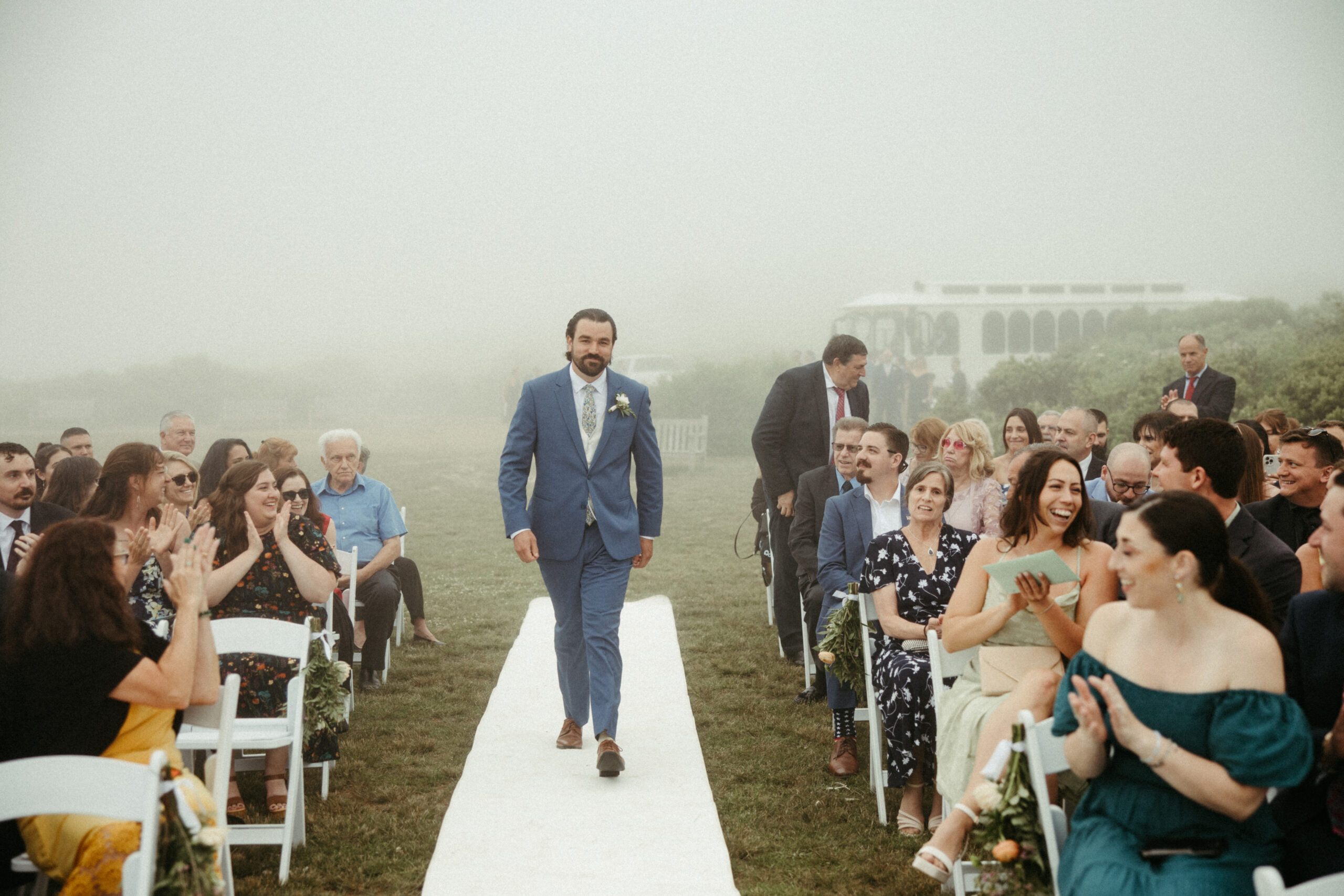 Groom walks down the aisle as fog hangs heavy in the air.