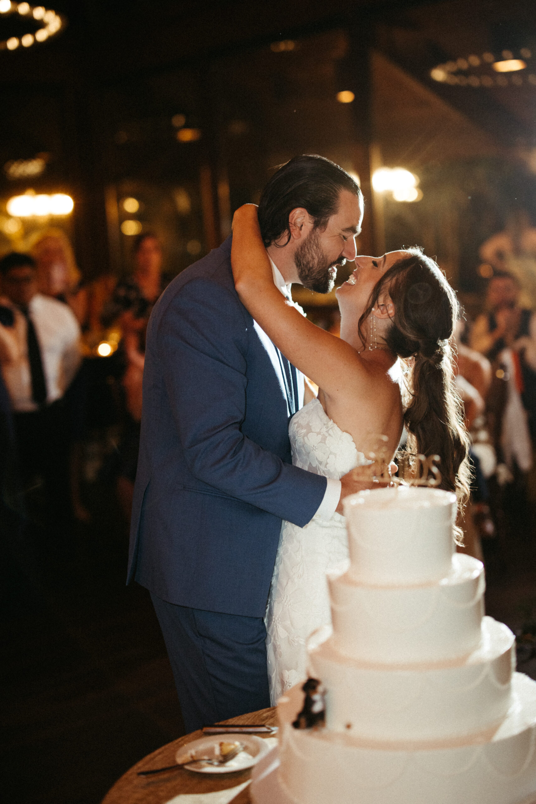 The couple share a happy kiss beside their wedding cake.