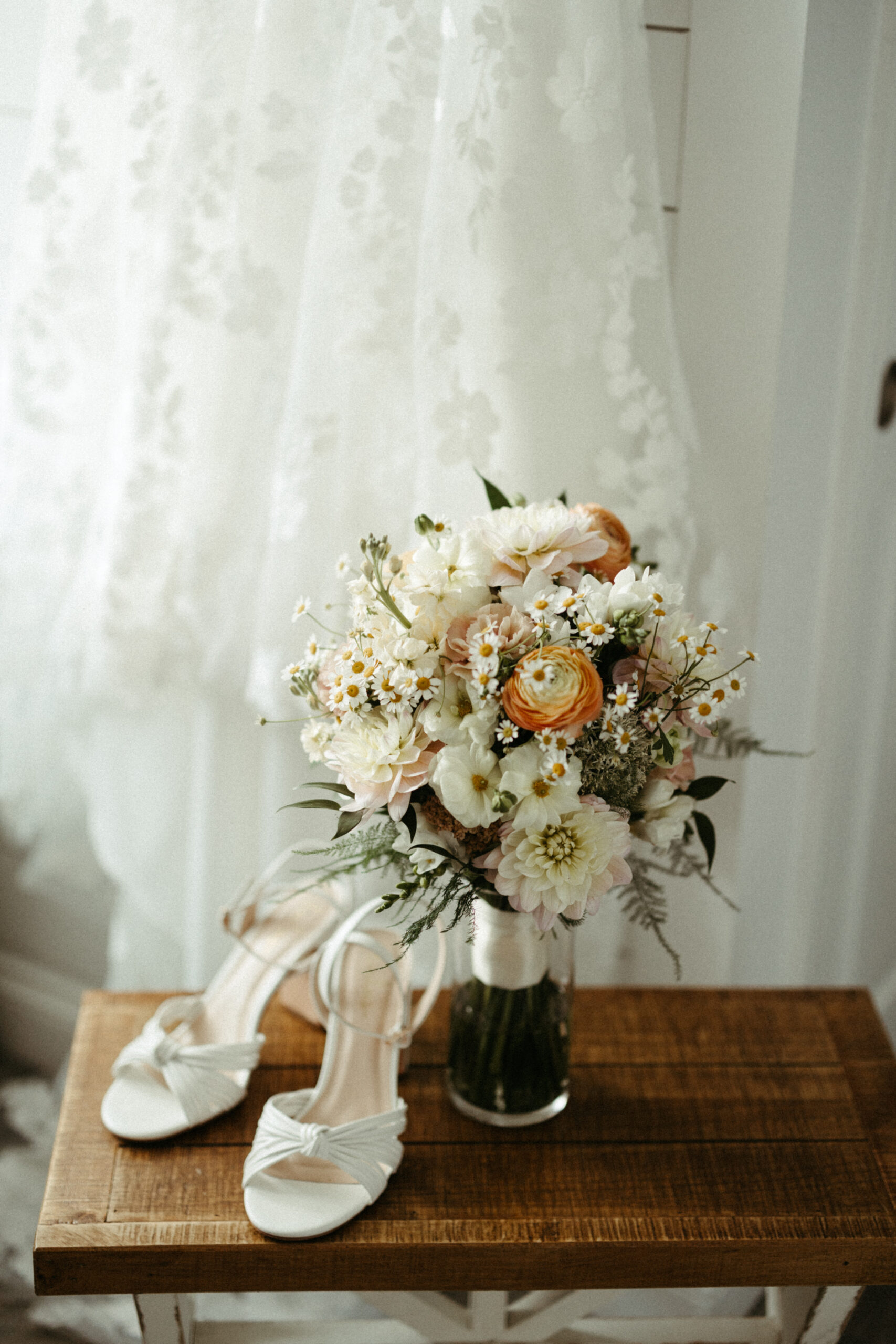 A detail photo of a bride's bouquet, shoes and the bottom of her wedding dress.