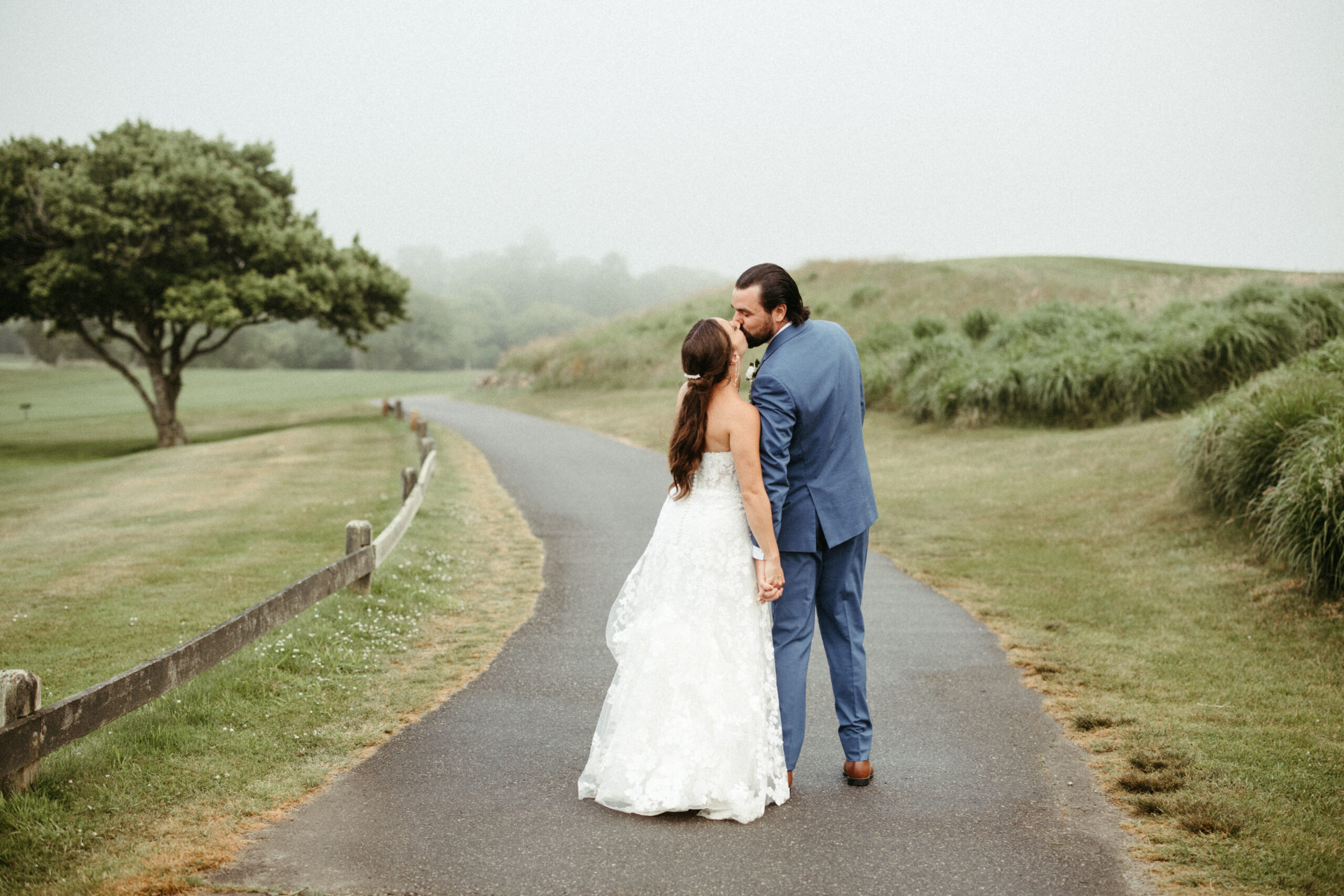 The couple stands on the golf course under a gray sky the last moments of their wedding day feeling peaceful and intimate.
