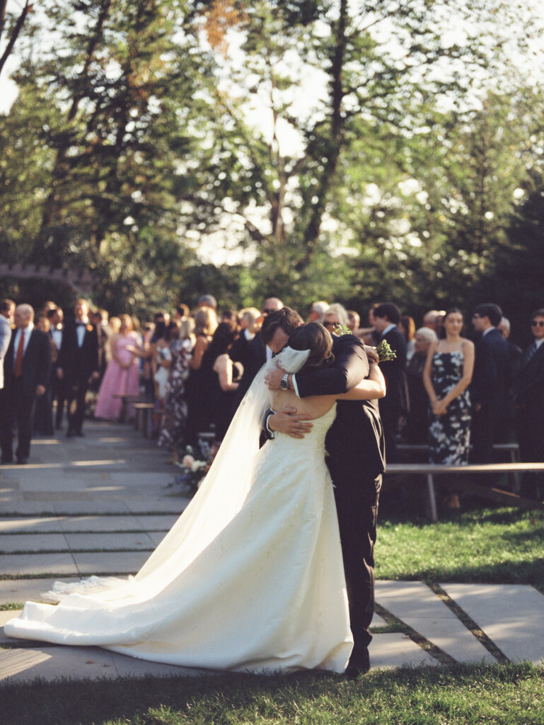 A couple embrace at the end of the wedding ceremony aisle, overcome with emotion after just getting married.