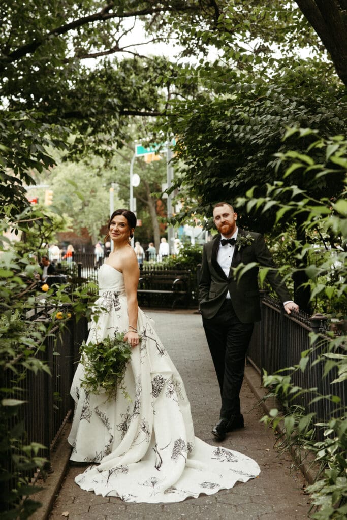Bride and groom walking through a leafy garden path in the West Village after their Houston Hall wedding