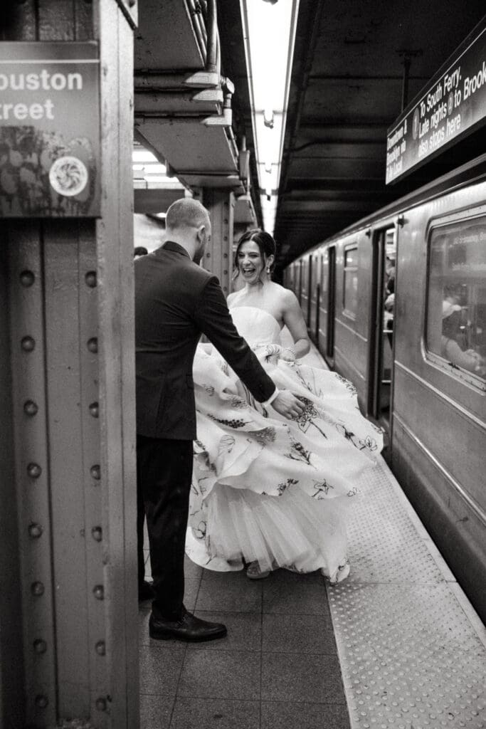 Bride twirling her wedding dress as groom reaches for her on a Houston Street subway platform in New York City