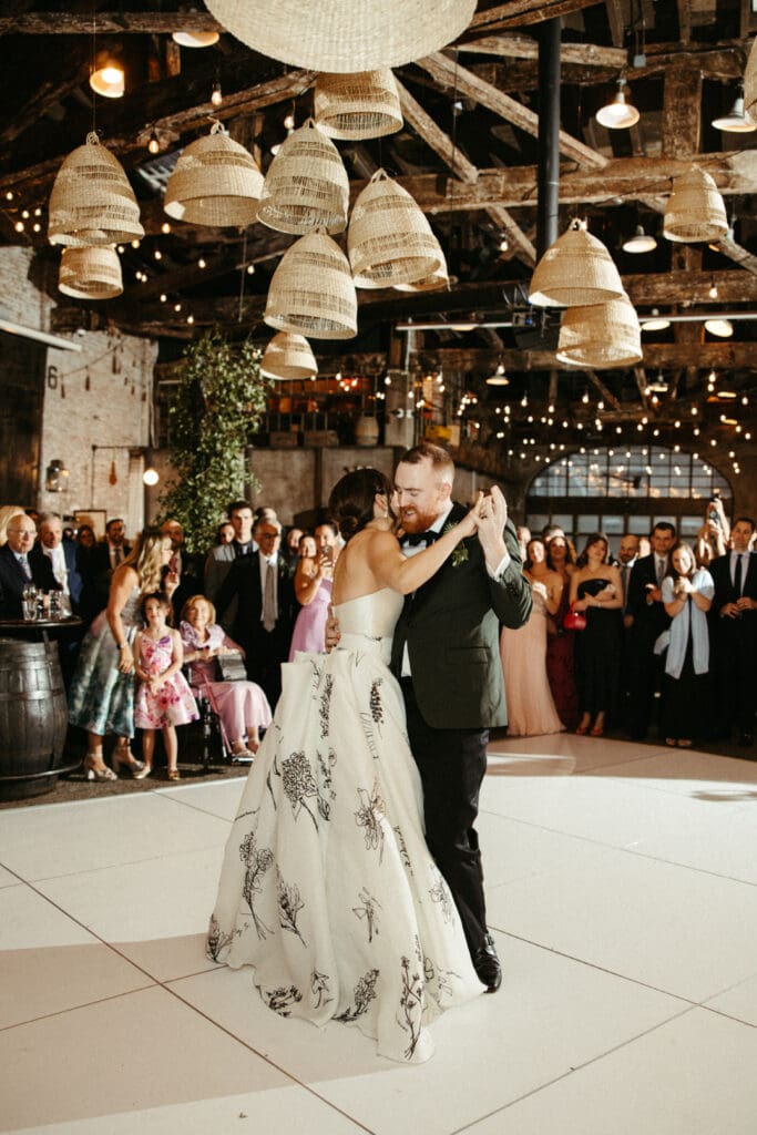 Bride and groom on the dance floor at their Houston Hall wedding as guests watch their first dance under string lights in the historic NYC venue