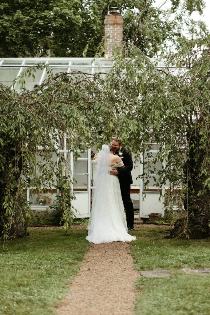 Bride and groom embrace during their private first look outside the greenhouse at Stone Acres Farm