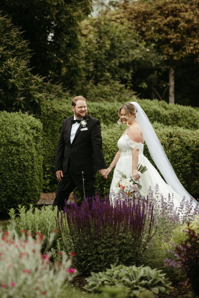 Bride and groom walking hand in hand through the gardens at Stone Acres Farm wedding in Stonington Connecticut