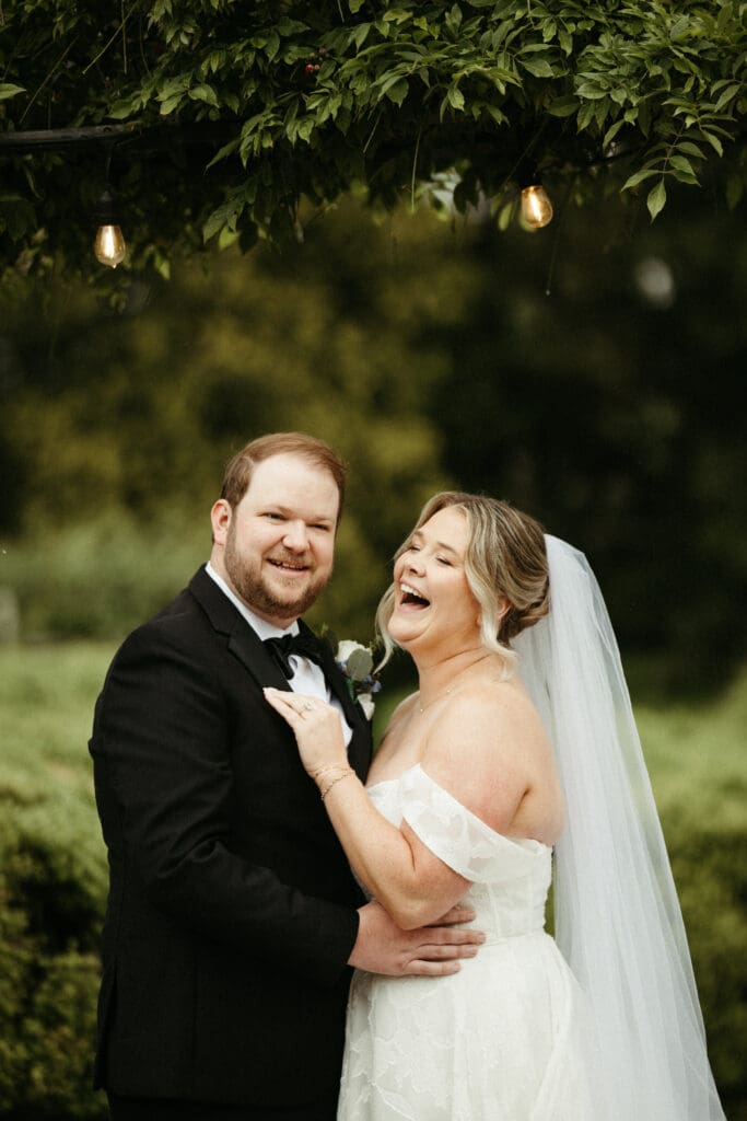 Bride and groom laughing together beneath string lights at Stone Acres Farm in Stonington Connecticut