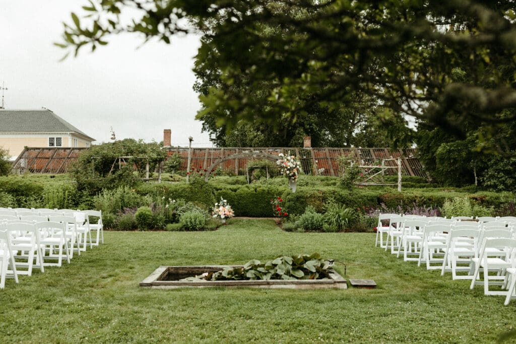 Outdoor garden ceremony setup with white chairs at Stone Acres Farm in Stonington, Connecticut for a Stone Acres Farm wedding