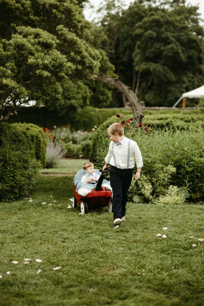 Children pulling a red wagon through the gardens at Stone Acres Farm during a joyful Stone Acres Farm wedding in Connecticut
