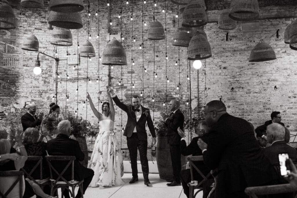 Adrianna and Jack walking back up the aisle as guests cheer and applaud after their Houston Hall wedding ceremony